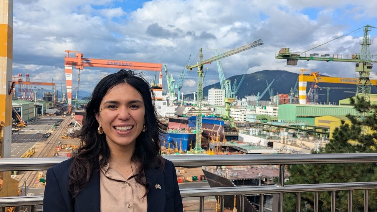 Photograph of NeuWave founder, Jana Stella, smiling in front of offshore construction site. 
