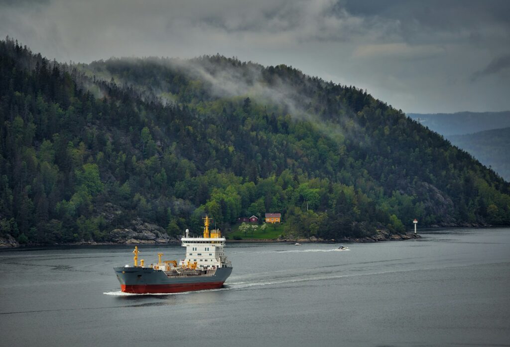 Photograph of service vessel in ocean, nearshore. Misty hills covered in trees in the background