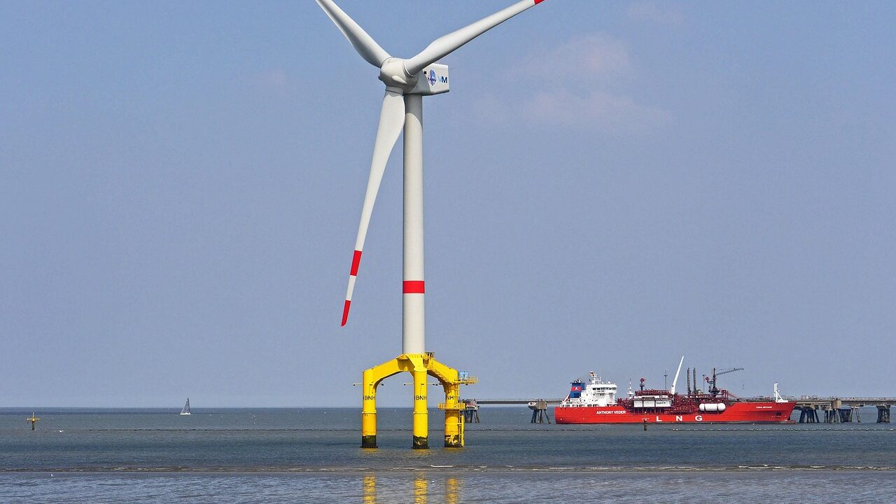 Photograph of service vessel travelling to shallow water offshore wind turbine. Clear blue skies and calm water