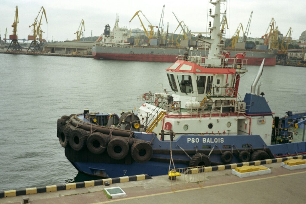 Red, white, and blue coloured commercial offshore vessel waiting in port. 